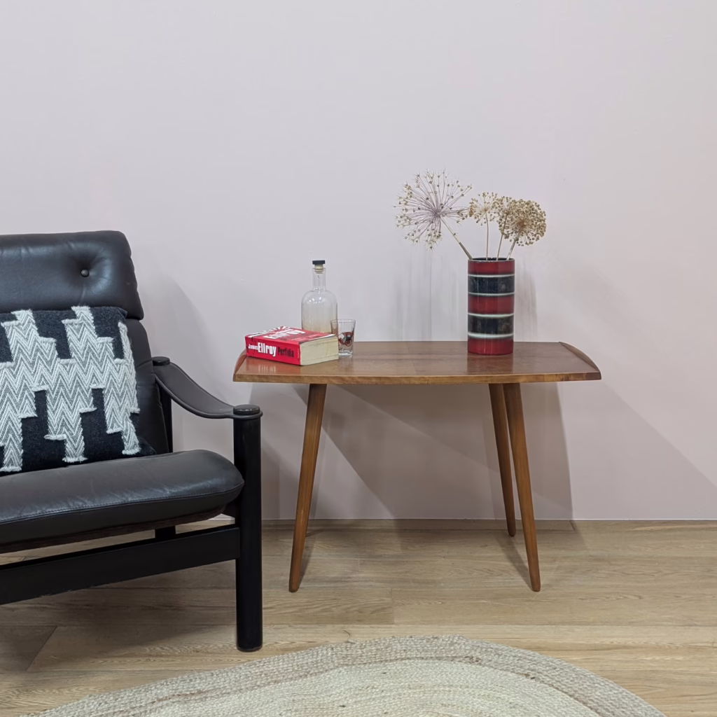 An unusual midcentury table, this. Taller than a conventional coffee table, the height is more akin to Scandinavian sofa tables, pieces that were designed to sit in front of the couch. But the width doesn't fit the sofa table brief - it's coffee table size. Regardless, it's a really handsome, useful piece used to the side for a lamp perhaps... or as a tall coffee table or small sofa table! We love the curved edges and the contoured lips at either end, the lighter bands of wood on the sides and the mirrored grain on the table top.  It's lightly marked but depending of its use, this may well not show. It's very faint. Those long legs unscrew so this is an item we can pack and send via UK courier too. We don't know its origins story but it would not surprise us if it hails from Scandinavia. The build quality and design strongly suggests this.  